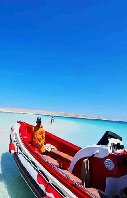Man in a boat on the beach, showcasing the Orange Bay island experience with a private speedboat adventure on the Red Sea.