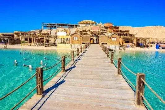 Wooden bridge over water with resort buildings, illustrating the Paradise Island with private speedboat and snorkeling adventure experience.