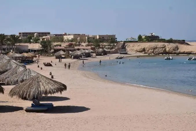 Snorkeling excursion to Mahmya Island in Hurghada, featuring straw umbrellas on a beach with people, showcasing the idyllic Red Sea experience.
