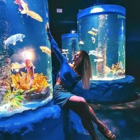 Woman interacts with fish at Hurghada Grand Aquarium, emphasizing ocean conservation and educational experiences in a vast underwater setting.