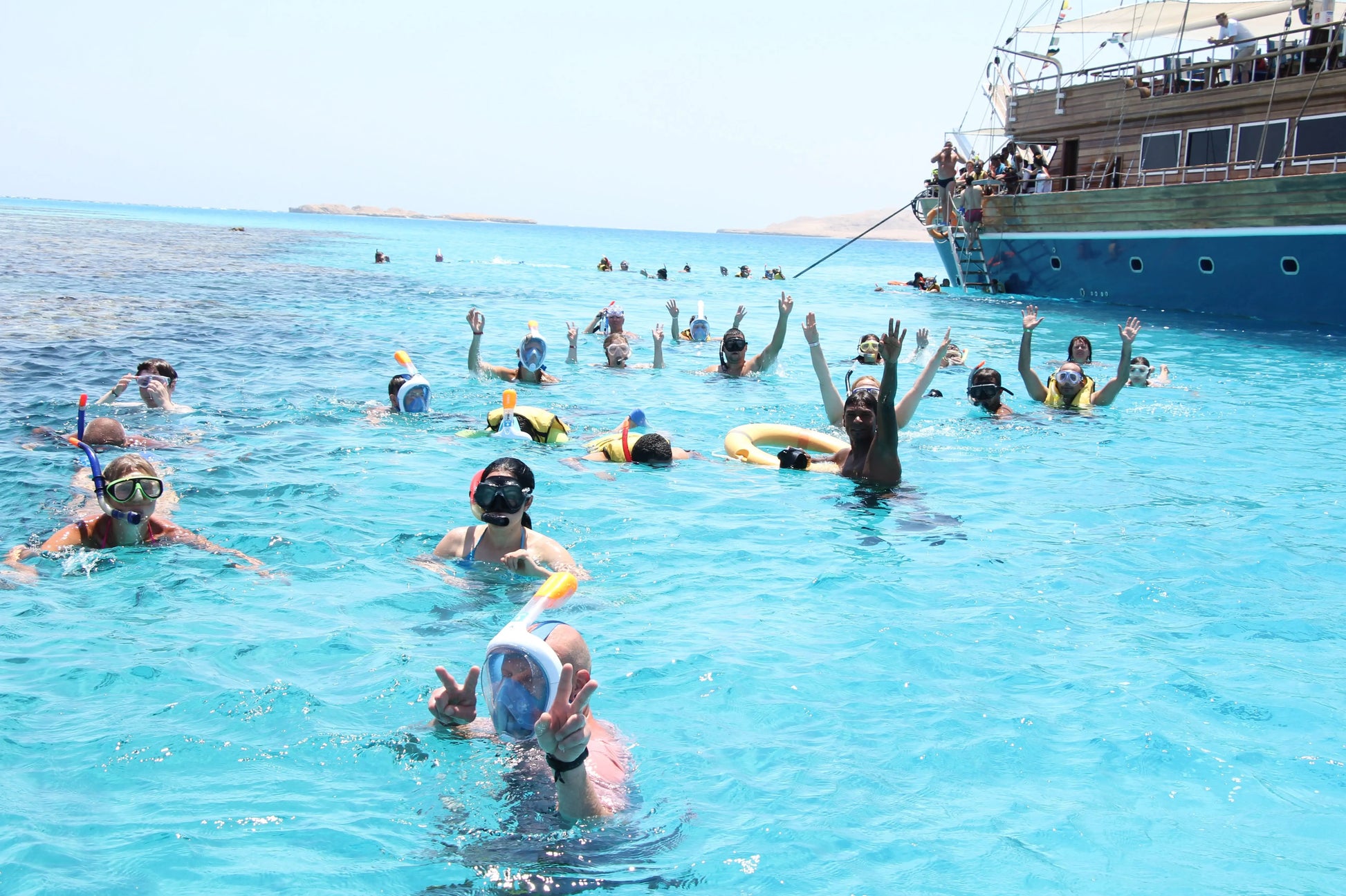 Group of people snorkeling in front of a pirate sailboat