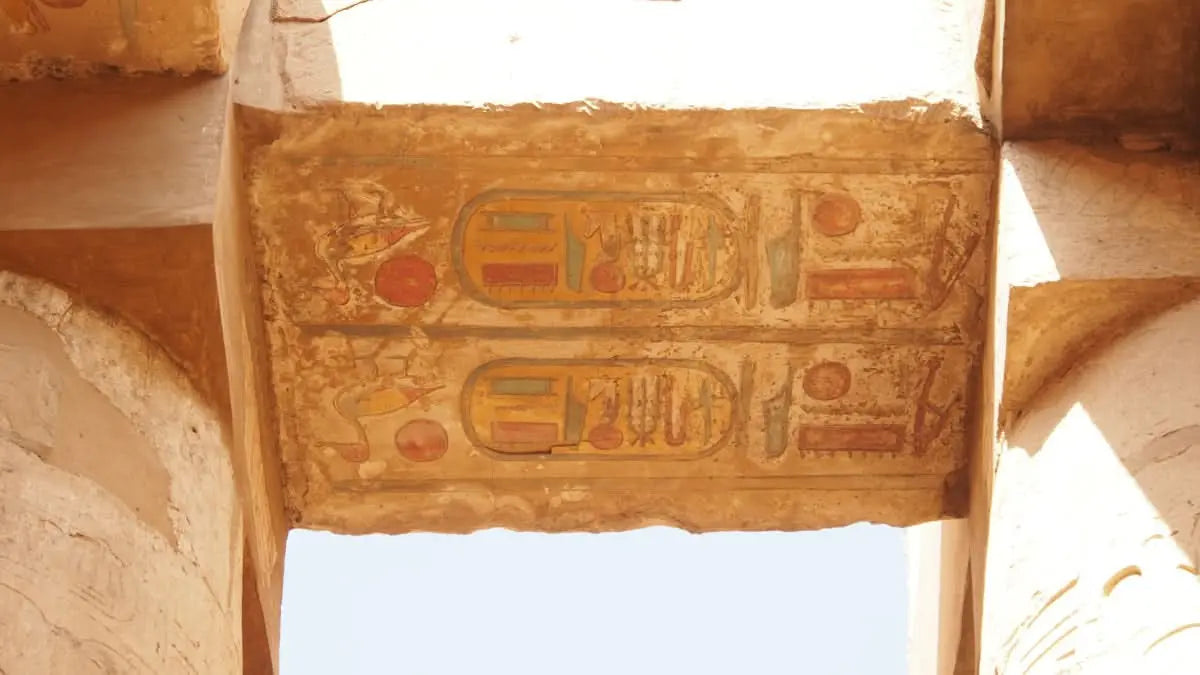 Pokryta hieroglifami kamienna ściana reprezentująca jednodniową wycieczkę do Luksoru z noclegiem, podkreślająca historyczną eksplorację starożytnych egipskich struktur i zabytków podczas tej wycieczki z przewodnikiem.