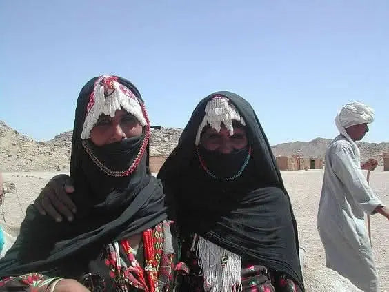 Women in black head coverings outdoors, signifying a cultural encounter during the 3-hour Safari with Quad-Bike and Camel Ride experience in the desert.