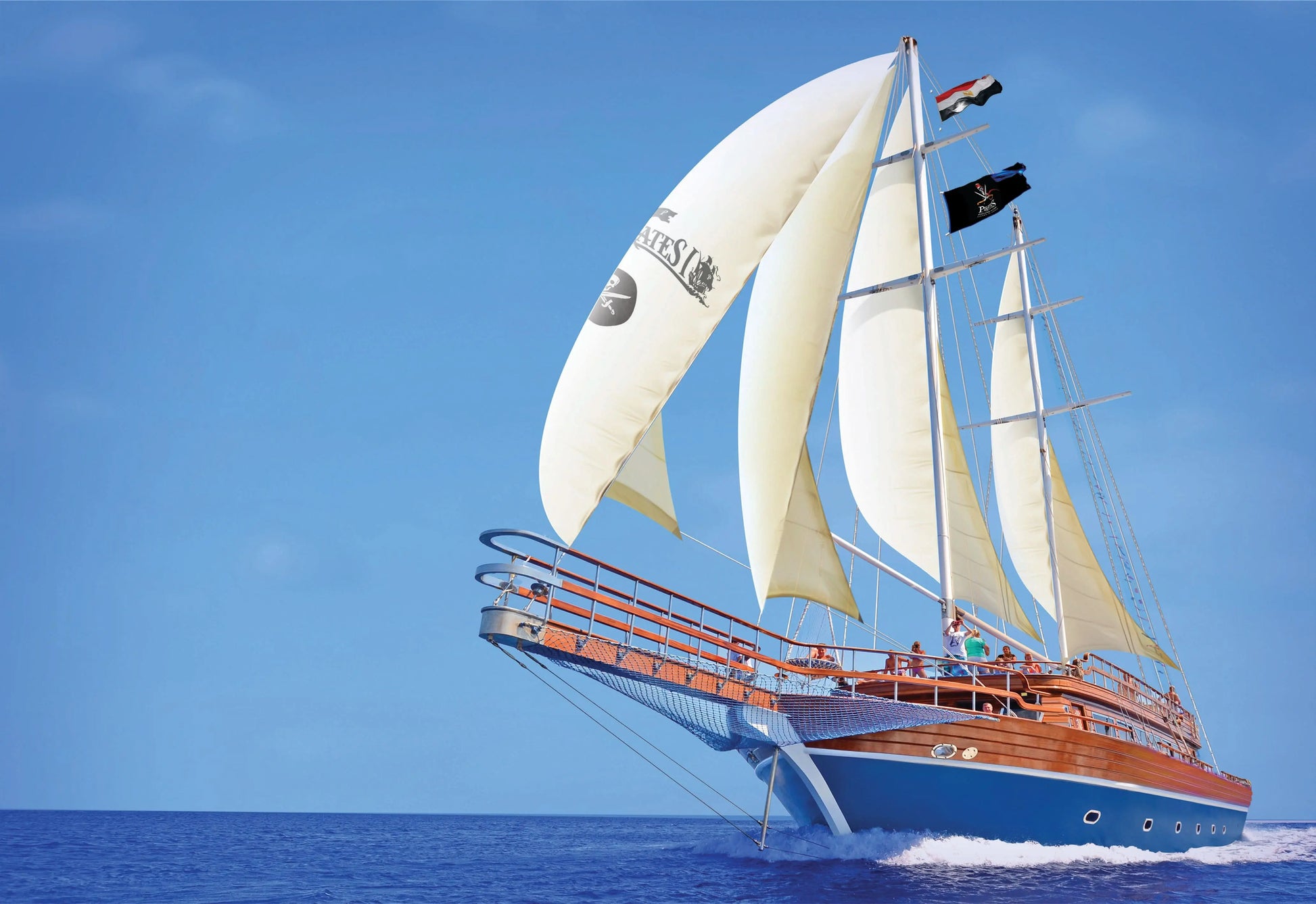 The sailing ship can be seen from the front, majestically sailing at full speed across the sea. The set sails stretch in the wind, while people are on the decks enjoying the journey and the maritime atmosphere.