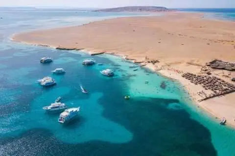 Snorkeling excursion to Mahmya Island with lunch; boats near a sandy beach, reflecting a day of exploration and relaxation at the Red Sea.