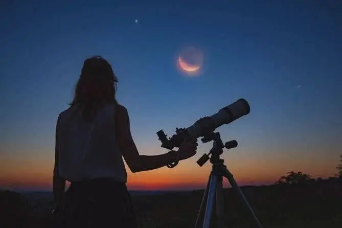 Woman using a telescope outdoors, observing the moon during the jeep safari with stargazing adventure, highlighting the astronomy experience against a desert sky backdrop.