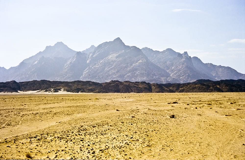 Day trip to Luxor: Scenic desert landscape with distant mountains, capturing the essence of the journey's natural beauty and historical allure.