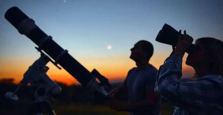 Group enjoying Jeep-Safari with Stargazing, featuring telescope use at sunset in the desert. Highlights include camel rides, Bedouin culture, and celestial views.