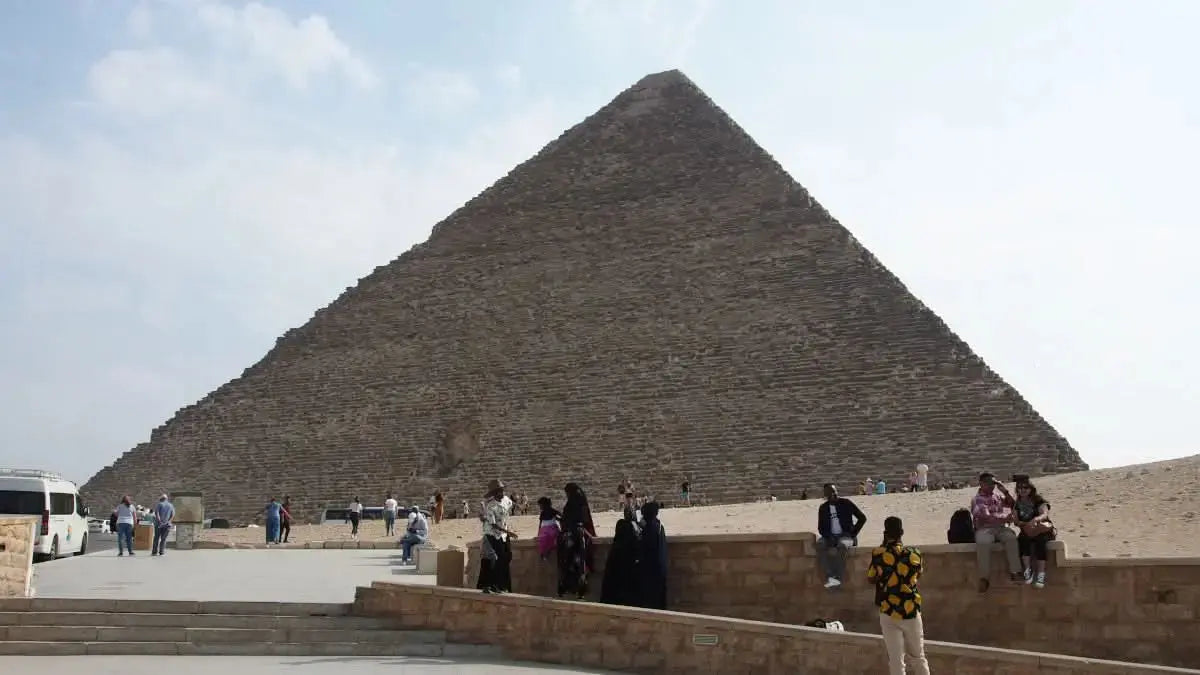 Tourists stand before the Giza Pyramids, part of the Cultural Tour to Cairo - 1 day, showcasing Egypt's historic wonders and architectural marvels.
