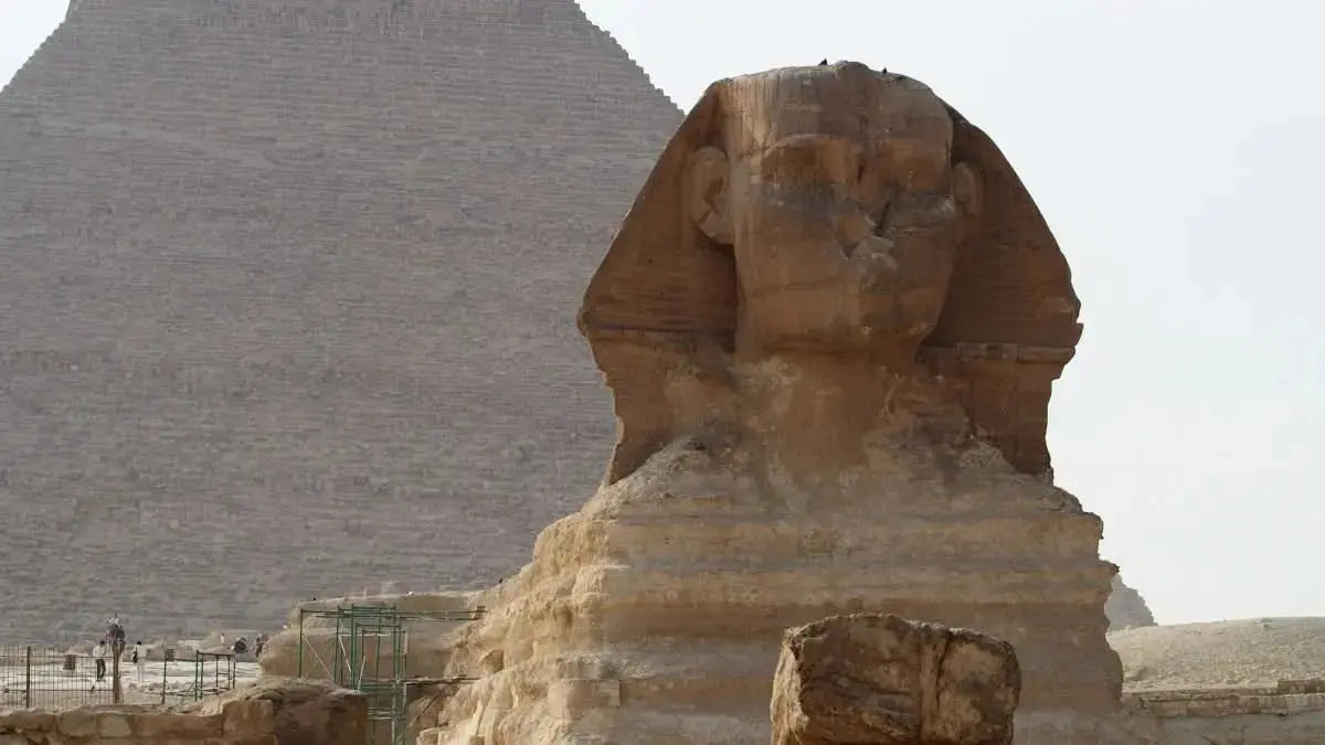 Cultural tour to Cairo - 1 day: A large stone statue stands majestically before the iconic Giza pyramids, evoking ancient Egyptian history and cultural exploration.