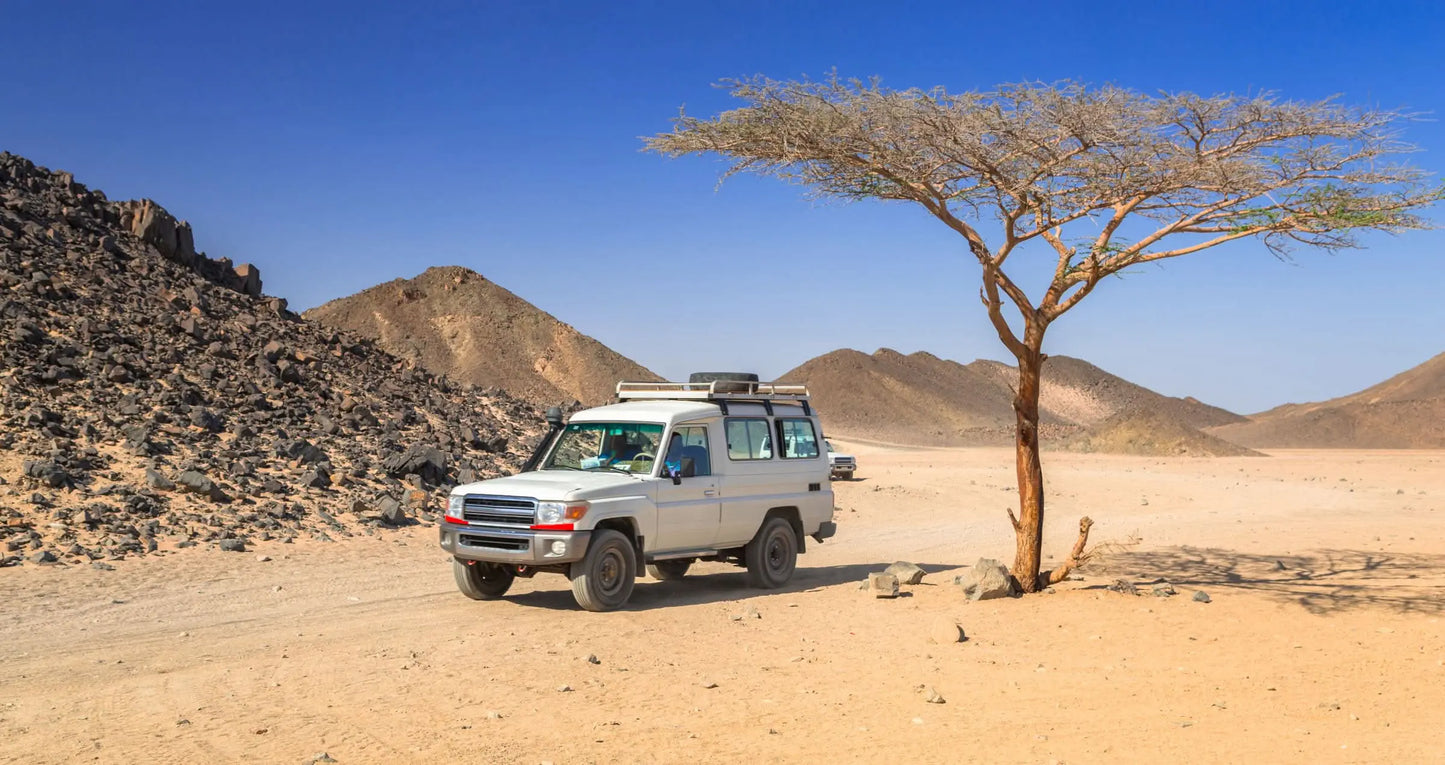 White truck on a dirt road during a Jeep-Safari with Stargazing experience, capturing adventure in the desert landscape, part of a unique travel itinerary.