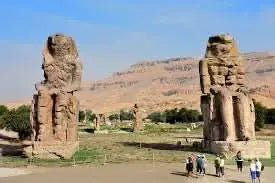 Day trip to Luxor: Group of people near ancient stone statues at an archaeological site, showcasing the historical ruins and monuments of Luxor.