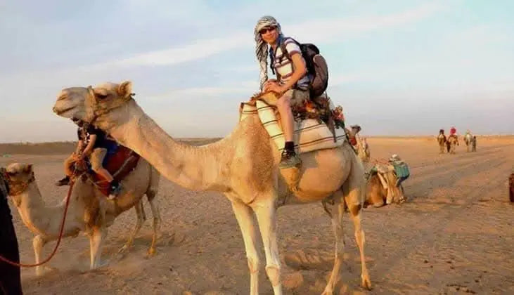 Man riding a camel in the desert, part of the jeep safari with stargazing experience, highlighting traditional exploration in a scenic, adventurous setting.