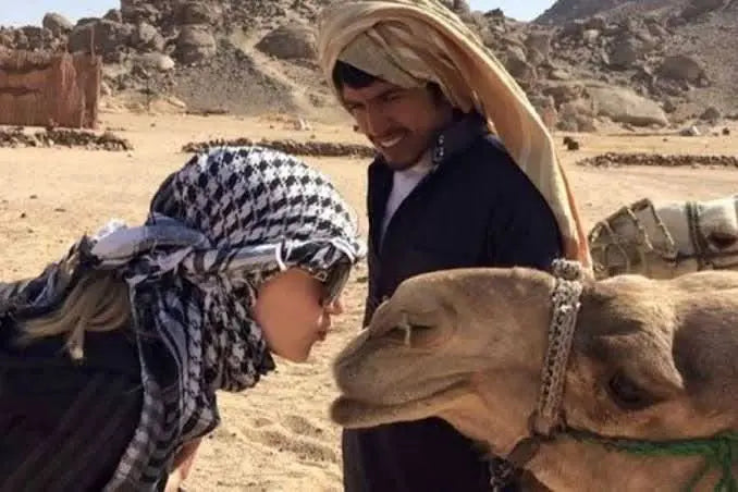 Man and woman with camels in a desert, illustrating the Jeep-Safari with Stargazing experience, highlighting traditional camel rides and Bedouin culture exploration.