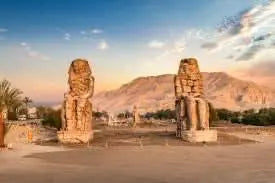 Statues in a desert landscape, representing the day trip to Luxor, highlighting iconic sites like the Colossi of Memnon and the Temple of Hatshepsut.