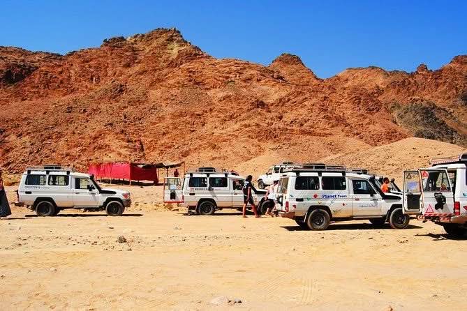 Jeep-Safari with Stargazing in El Gouna showcasing parked desert vehicles, including a white van, highlighting adventure and cultural experiences amidst stunning landscapes.