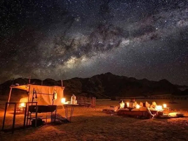 Jeep-Safari with Stargazing: A group sits by a campfire under a starry sky, highlighting the adventure's celestial focus and desert experience.