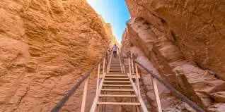 Luxor Day Trip: A person ascends a staircase in a canyon, symbolizing exploration of ancient Egyptian sites like Karnak Temple and the Valley of the Kings.