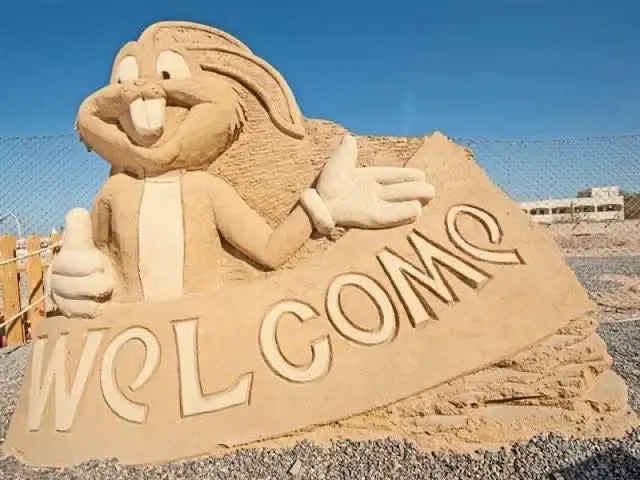 Sand City Museum: Zewnętrzna rzeźba z piasku przedstawiająca królika trzymającego znak, prezentująca kreatywny kunszt w unikalnej koncepcji muzeum na świeżym powietrzu.