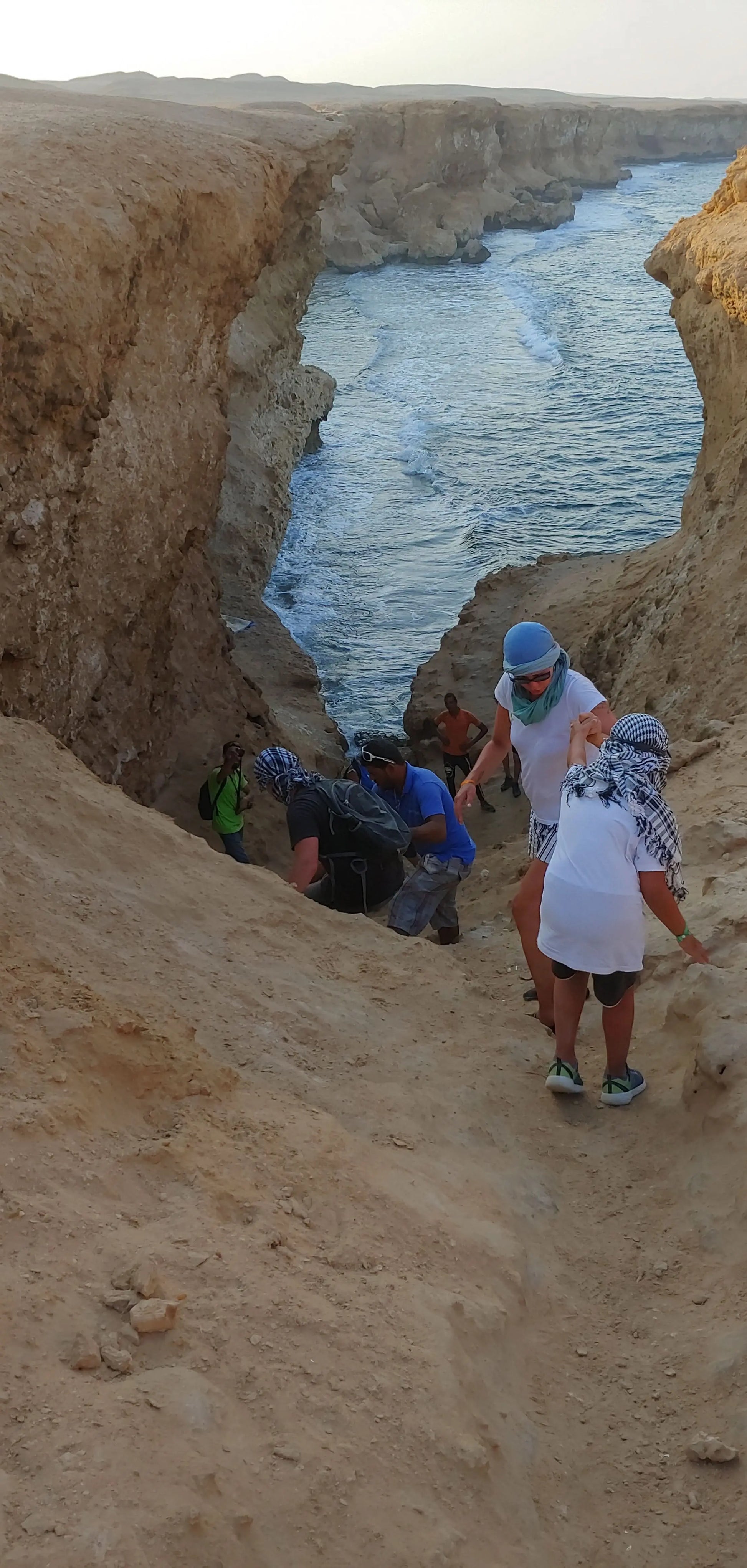 Group climbing a cliff, representing the adventurous spirit of the 3 Stunden Safari mit Quad-Bike und Kamelritt, highlighting the exciting desert exploration experience.