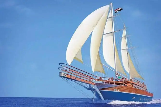 Ein beeindruckendes großes Segelschiff gleitet über das Meer mit voll gesetzten Segeln. Die Rumpfunterseite ist in Blau gehalten, während ab der Mitte eine edle Holzverkleidung beginnt. Das Schiff wirkt modern und schnittig, strahlt zugleich aber eine maritime Eleganz aus – perfekt für Abenteuerlustige, die das Meer lieben.