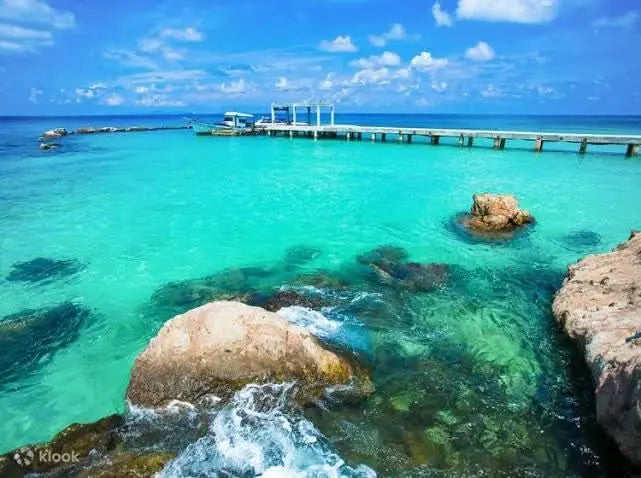 Eden Island Tour: A serene view of a dock surrounded by rocks and clear water under a blue sky, representing the tranquil adventure awaiting in Hurghada.