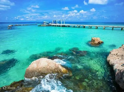 Eden Island Tour: A serene view of a dock surrounded by rocks and clear water under a blue sky, representing the tranquil adventure awaiting in Hurghada.