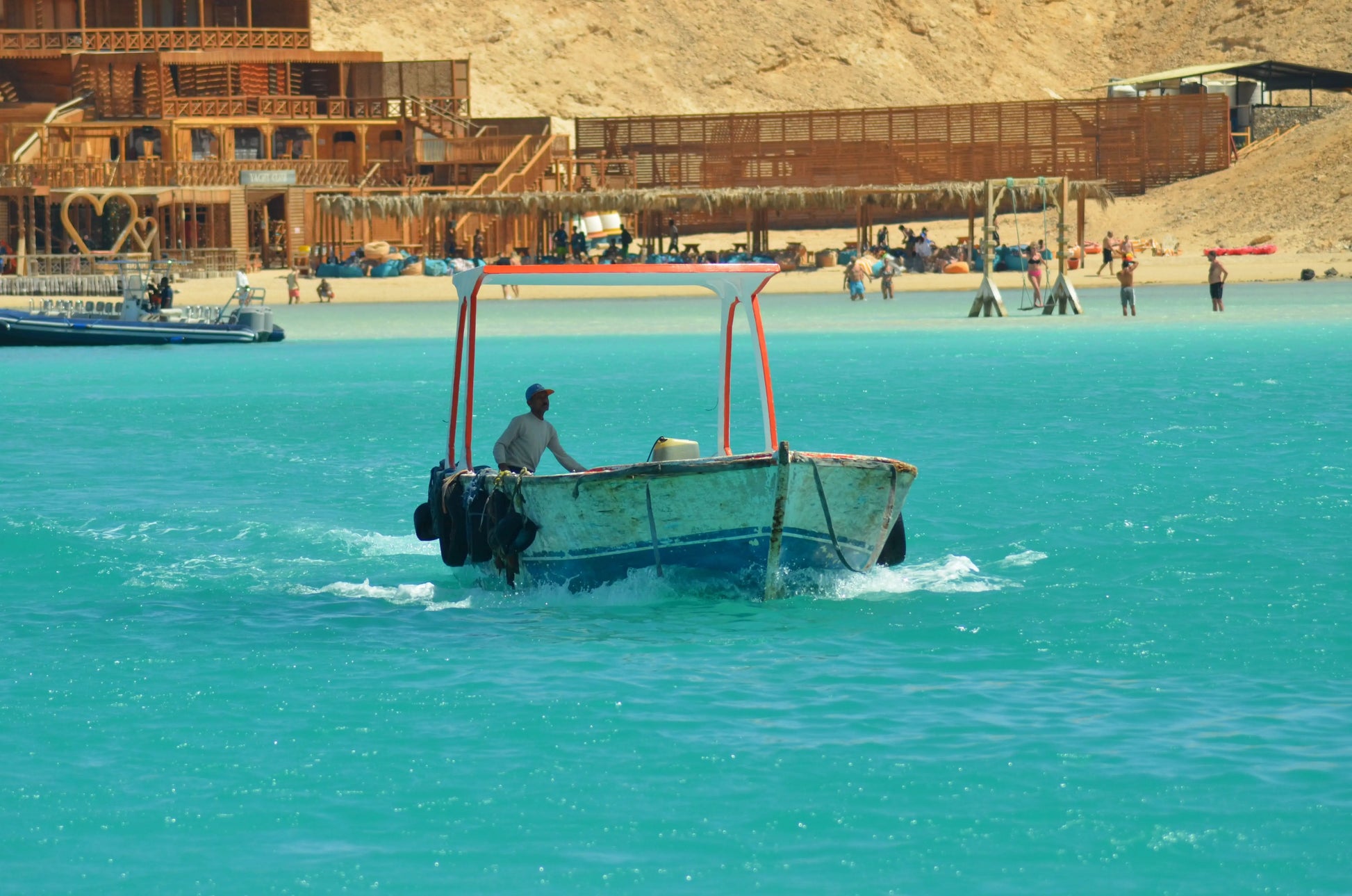 Man enjoying Orange Bay Tour adventure on a boat, preparing for snorkeling and exploring vibrant coral reefs in Hurghada's serene waters.