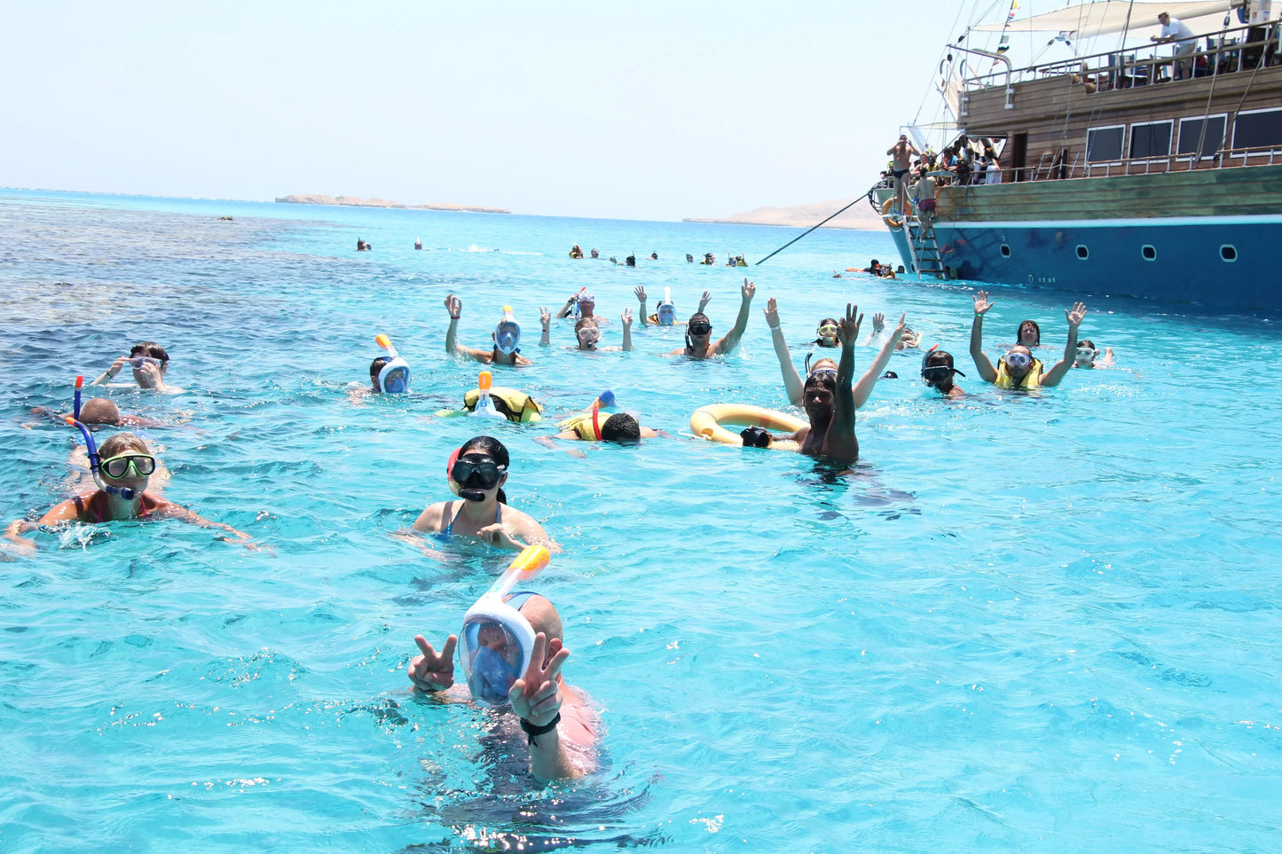 Group of people snorkeling in front of a pirate sailboat