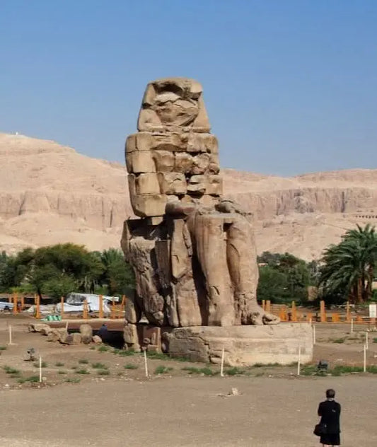 Luxor Day Trip: Features a large stone statue in a desert setting, reminiscent of the Colossi of Memnon, highlighting Egypt's historical grandeur.