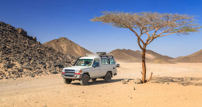 White truck on a dirt road during a Jeep-Safari with Stargazing experience, capturing adventure in the desert landscape, part of a unique travel itinerary.
