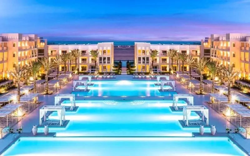Jaz Makadi Aquaviva Waterworld: A vibrant image showcasing pools surrounded by palm trees and buildings, epitomizing a fun-filled day at Hurghada's largest water-themed park.