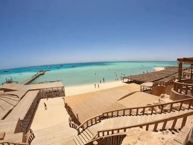 Paradise Island with private speedboat and snorkeling adventure, featuring a wooden walkway leading to a pristine beach with a clear blue sky.