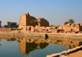 Luxor day tour: Explore ancient ruins and Nile views, featuring stone buildings and palm trees, including an overnight stay.