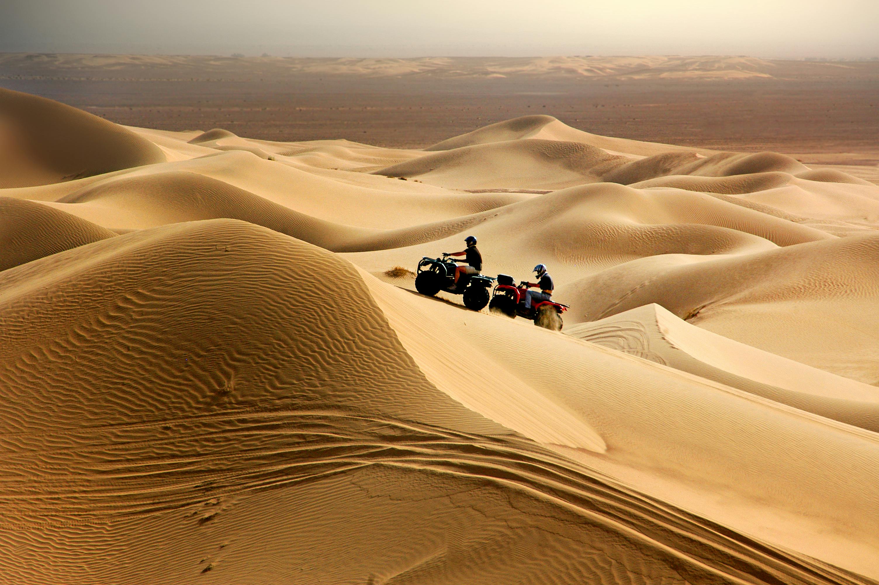 2 quad bikers on a dune