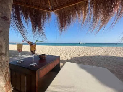 Dwa kieliszki na stoliku na plaży, symbolizujące relaks. Przeżyj Eden Island Tour, odkrywając cuda Morza Czerwonego podczas tej wyjątkowej przygody z nurkowaniem z rurką.