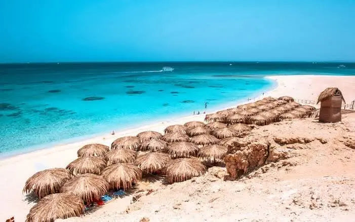 Eden Island Tour: Przeżyj plażową scenerię ze słomianymi parasolami, łodzią na lazurowych wodach, idealną na niezapomnianą przygodę z nurkowaniem w Hurghadzie.